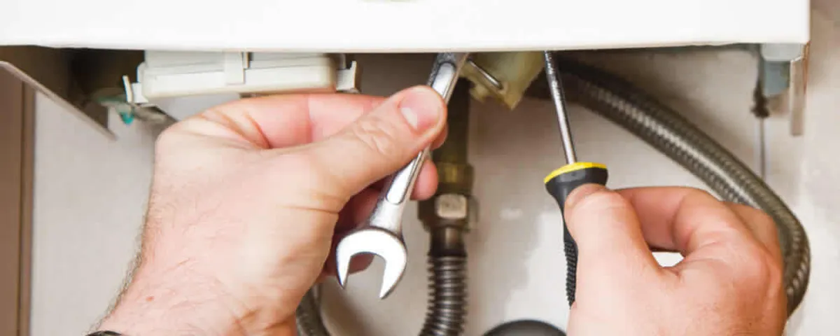 Boiler repair technician tightening pipe fittings and connections in Burlington, MA