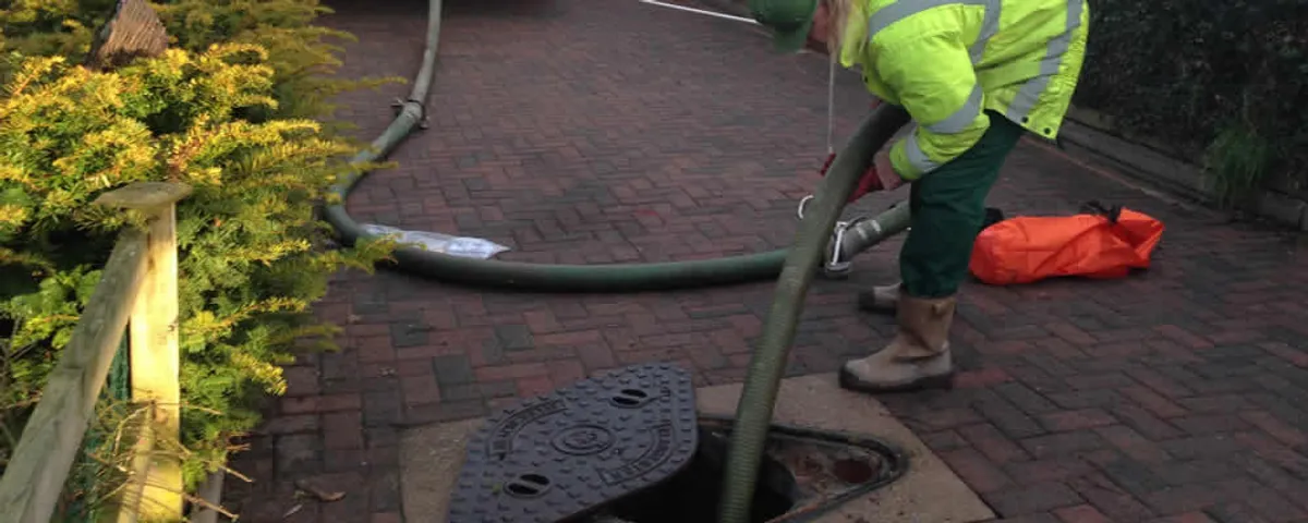 Septic tank cleaning technician servicing a septic tank with a vacuum hose in Burlington, MA