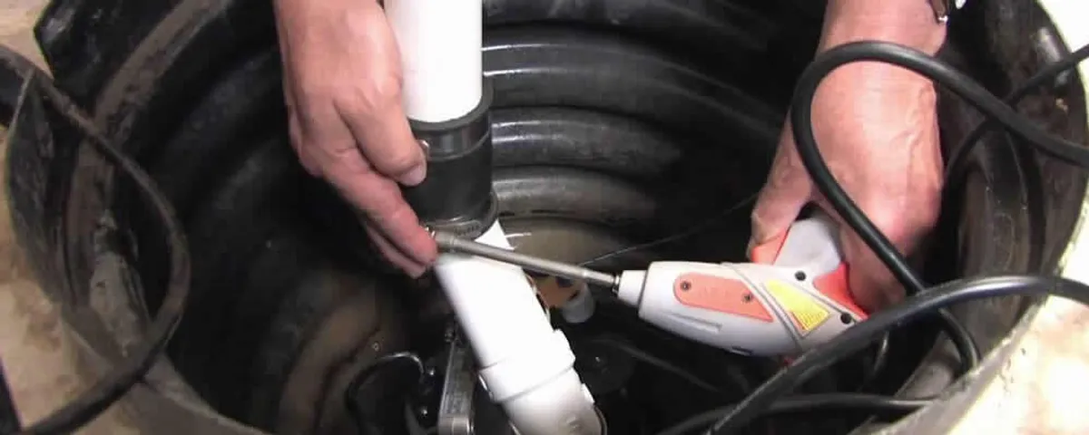 Sump pump installation technician connecting PVC discharge piping in Burlington, MA