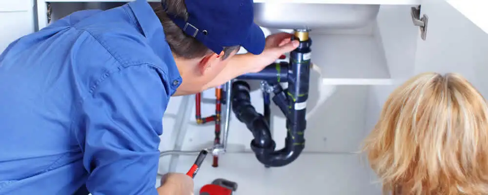 Plumber repairing under-sink drain pipes and fittings in Burlington, MA